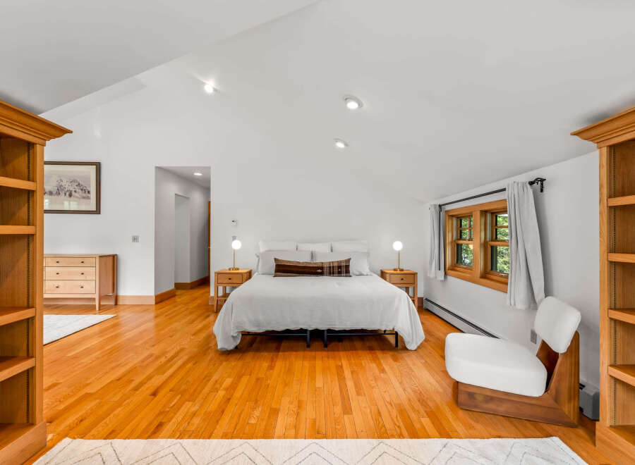 This spacious bedroom features a large, comfortable bed with crisp white linens, complemented by two wooden nightstands with lamps.