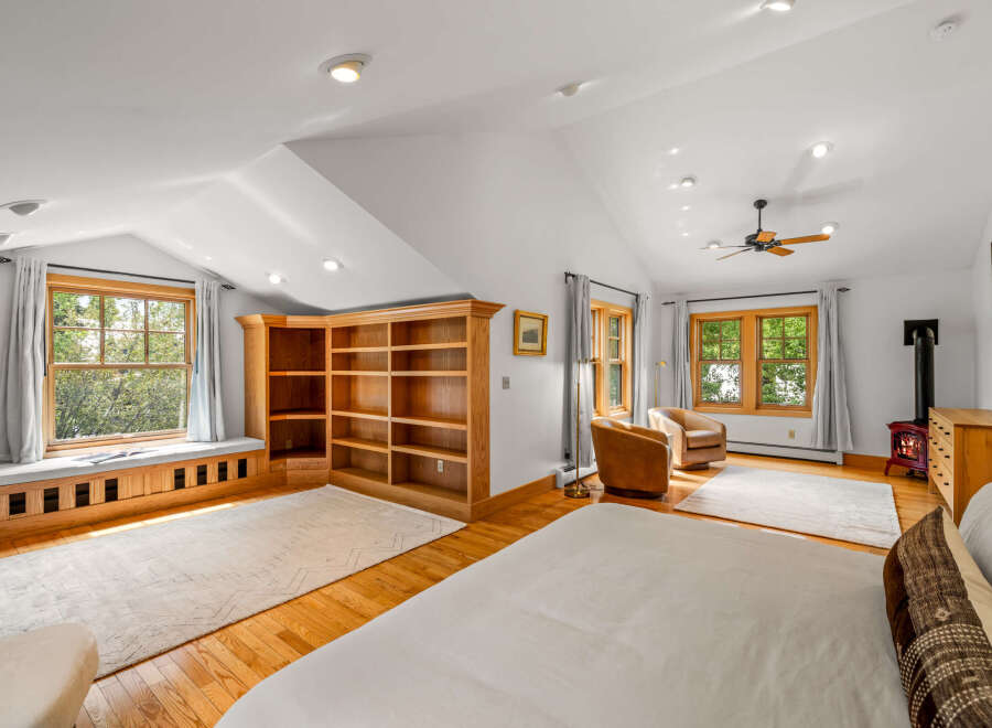Discover this charming attic bedroom featuring a cozy window seat overlooking lush greenery, perfect for relaxation.