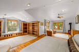 Discover this charming attic bedroom featuring a cozy window seat overlooking lush greenery, perfect for relaxation.