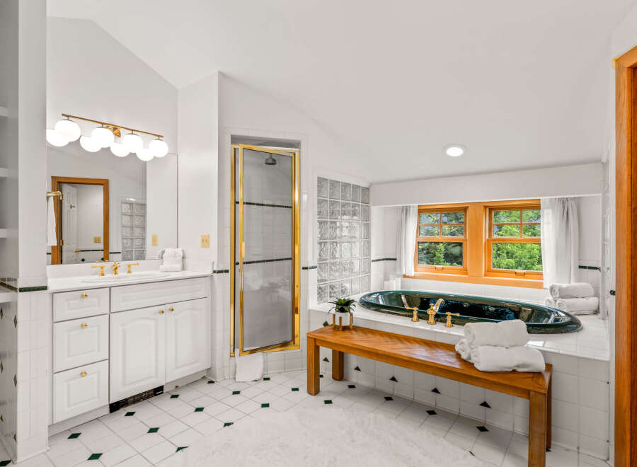 Indulge in luxury in this stunning bathroom featuring a deep soaking tub with elegant gold fixtures, perfect for unwinding.