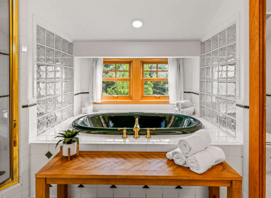 Indulge in luxury in this stunning bathroom featuring a deep soaking tub with elegant gold fixtures.
