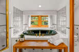Indulge in luxury in this stunning bathroom featuring a deep soaking tub with elegant gold fixtures.