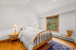 This charming bedroom features a cozy queen-sized bed with crisp white linens, perfect for a restful night's sleep.