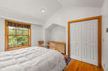 This charming bedroom features a large window with a colorful roman shade, offering a view of lush greenery.