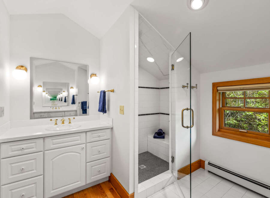 This bright and airy bathroom features a spacious vanity with ample storage and elegant gold fixtures.