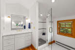 This bright and airy bathroom features a spacious vanity with ample storage and elegant gold fixtures.