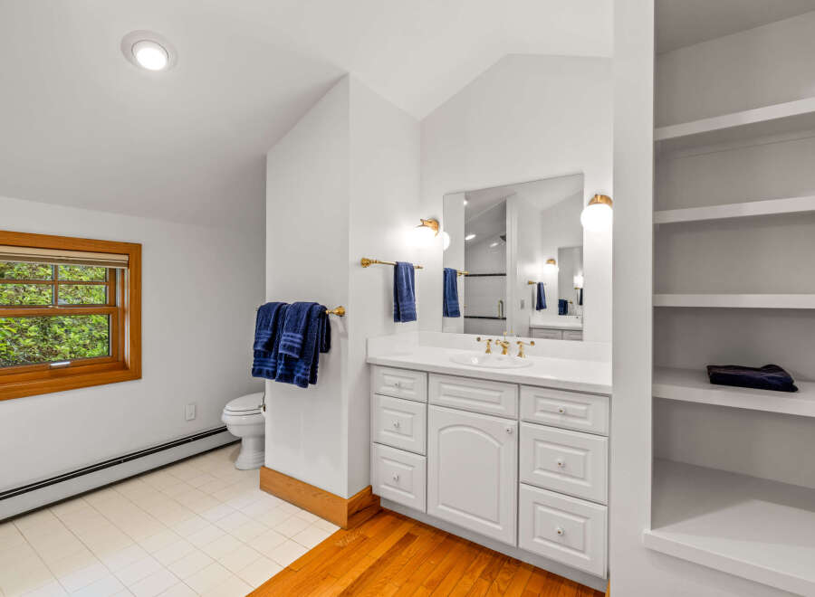 This bright and airy bathroom features a spacious vanity with ample storage and a large mirror, perfect for your morning routine.