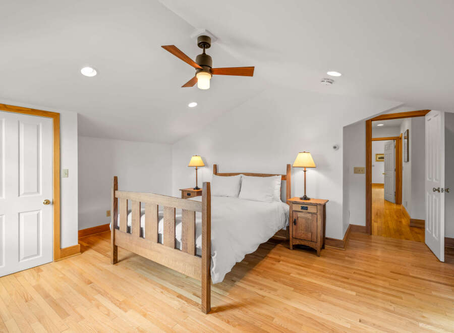 This charming bedroom features a rustic wooden bed frame complemented by crisp white linens, creating a serene and inviting atmosphere.