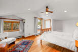 This charming bedroom features a cozy wooden bed dressed in crisp white linens, complemented by a vibrant oriental rug on the gleaming hardwood floor.