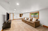 This spacious basement living area features a comfortable brown sectional sofa adorned with plush pillows, perfect for relaxing.