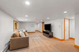 This spacious basement living area features a comfortable brown sofa with accent pillows, perfect for relaxing.