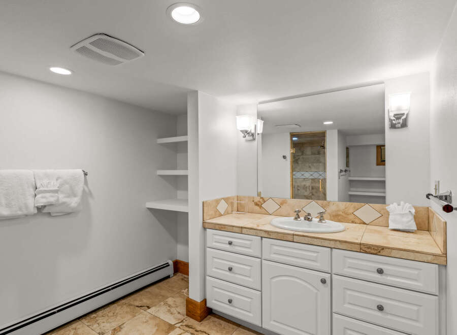 This spacious bathroom features a large vanity with ample storage and a beautiful tiled countertop.
