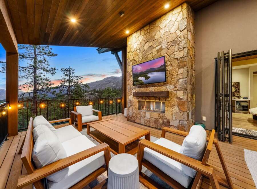 Experience luxury outdoor living with this stunning covered patio, featuring a cozy seating area around a modern fireplace and a large flat-screen TV.