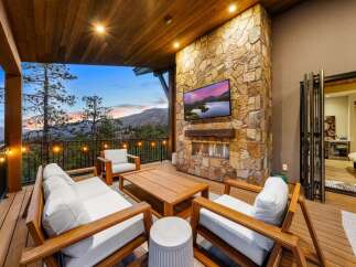 Experience luxury outdoor living with this stunning covered patio, featuring a cozy seating area around a modern fireplace and a large flat-screen TV.