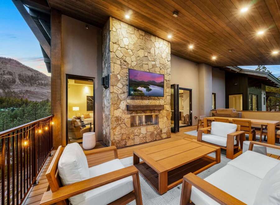 Experience luxurious outdoor living with this stunning patio featuring a modern stone fireplace and a large flat-screen TV, perfect for entertaining guests year-round.