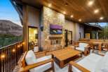Experience luxurious outdoor living with this stunning patio featuring a modern stone fireplace and a large flat-screen TV, perfect for entertaining guests year-round.