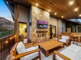 Experience luxurious outdoor living with this stunning patio featuring a modern stone fireplace and a large flat-screen TV, perfect for entertaining guests year-round.