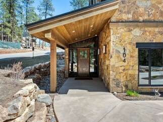 Discover modern mountain living with this stunning home featuring a striking stone facade and a dramatic angled wood-paneled entryway.