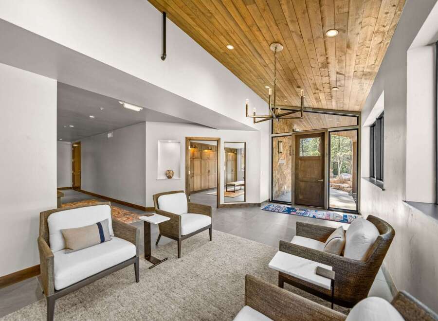 Step into a grand entryway featuring a stunning wood-paneled ceiling and a modern chandelier, creating a warm and inviting atmosphere.