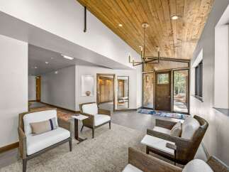 Step into a grand entryway featuring a stunning wood-paneled ceiling and a modern chandelier, creating a warm and inviting atmosphere.