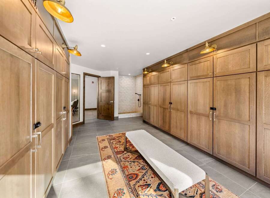 Discover this spacious walk-in closet featuring custom wood cabinetry for ample storage and a built-in bench for comfortable dressing.