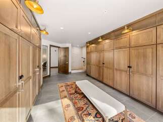 Discover this spacious walk-in closet featuring custom wood cabinetry for ample storage and a built-in bench for comfortable dressing.