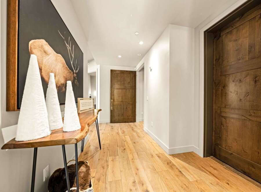 Step into this inviting hallway featuring warm, natural wood flooring and rustic wooden doors.