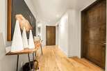 Step into this inviting hallway featuring warm, natural wood flooring and rustic wooden doors.