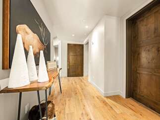 Step into this inviting hallway featuring warm, natural wood flooring and rustic wooden doors.