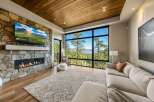 Experience breathtaking mountain views from this stunning living room, featuring a modern gas fireplace set against a natural stone accent wall.