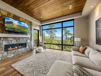 Experience breathtaking mountain views from this stunning living room, featuring a modern gas fireplace set against a natural stone accent wall.