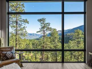 Experience breathtaking panoramic views from this stunning property, featuring expansive floor-to-ceiling windows that frame a majestic mountain landscape.