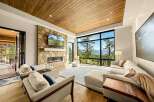 Experience breathtaking mountain views from this stunning living room, featuring a modern stone fireplace and a large, wall-to-wall window.