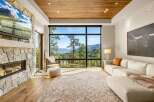 Experience breathtaking mountain views from this stunning living room, featuring a modern stone fireplace and a large, picturesque window.