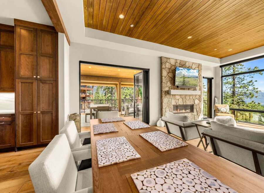 Experience luxury mountain living in this stunning home featuring a spacious dining area with a rustic wooden table and elegant placemats.