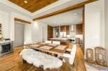 Experience modern luxury in this open-concept living space, featuring a stunning wood-paneled ceiling with exposed beams and a sleek, gourmet kitchen.