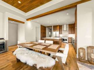Experience modern luxury in this open-concept living space, featuring a stunning wood-paneled ceiling with exposed beams and a sleek, gourmet kitchen.