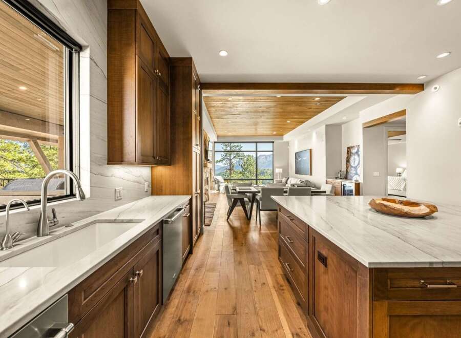 Experience luxury living in this stunning modern kitchen, featuring rich wood cabinetry and sleek marble countertops.