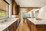 Experience luxury living in this stunning modern kitchen, featuring rich wood cabinetry and sleek marble countertops.
