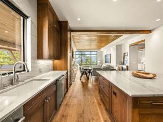 Experience luxury living in this stunning modern kitchen, featuring rich wood cabinetry and sleek marble countertops.