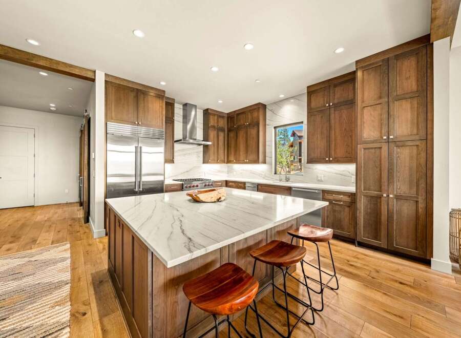 Experience luxury in this stunning modern kitchen, featuring rich wood cabinetry and a sleek marble island perfect for entertaining.