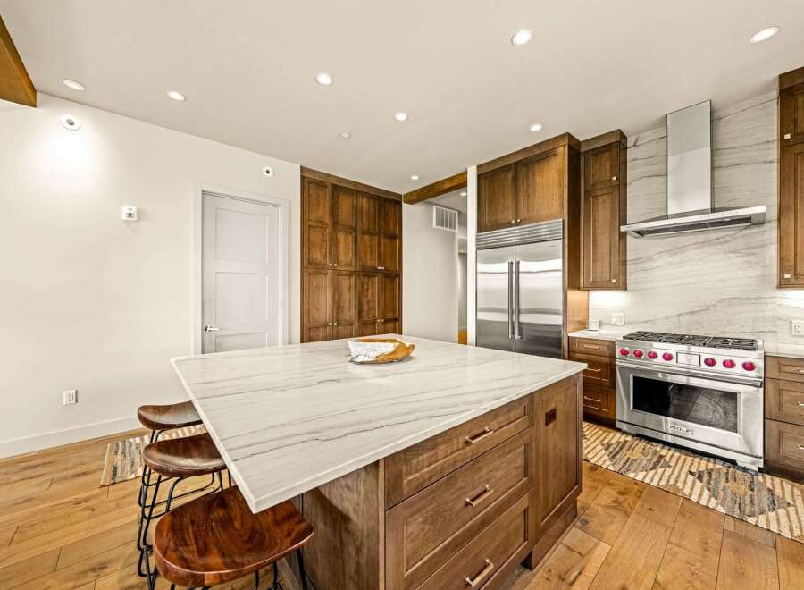 Experience luxury in this stunning gourmet kitchen, featuring a large marble island with seating and custom wood cabinetry.