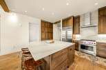 Experience luxury in this stunning gourmet kitchen, featuring a large marble island with seating and custom wood cabinetry.