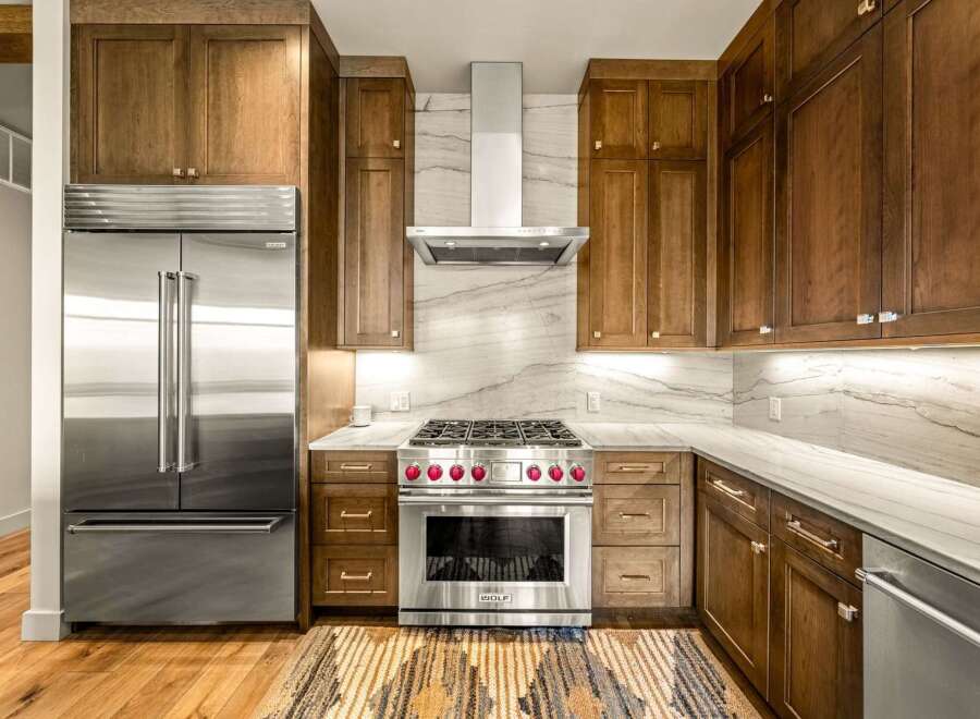 Experience luxury in this stunning kitchen featuring custom wood cabinetry and a professional-grade Wolf range with striking red knobs.