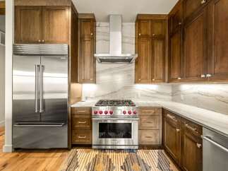 Experience luxury in this stunning kitchen featuring custom wood cabinetry and a professional-grade Wolf range with striking red knobs.