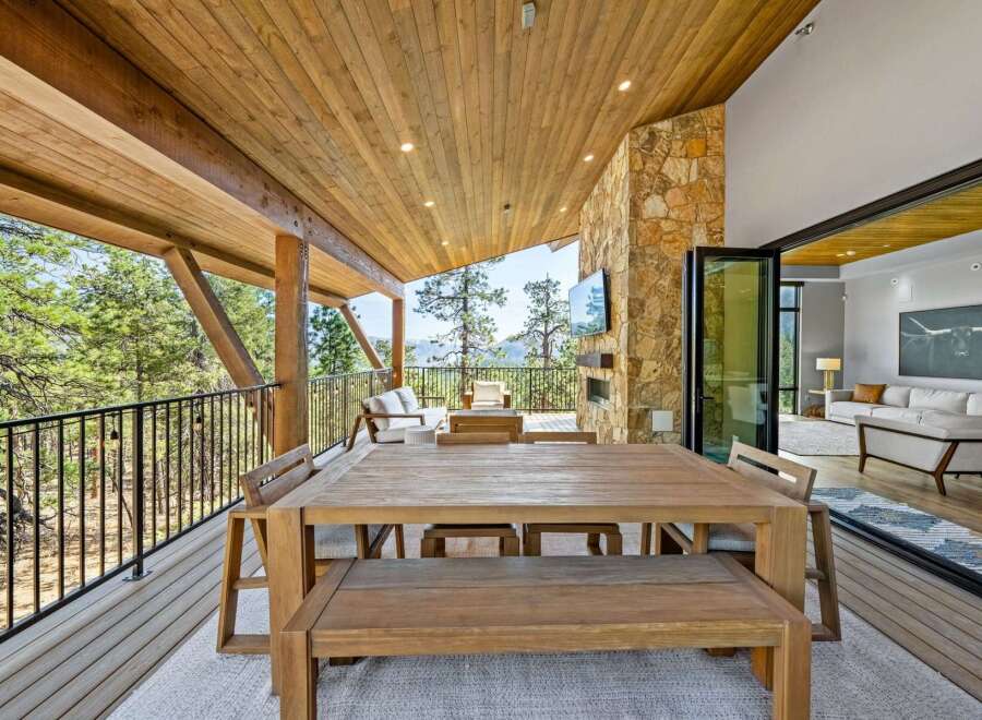 Experience luxurious indoor-outdoor living with this stunning covered patio, featuring a spacious dining area and a cozy seating space with a fireplace.