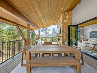 Experience luxurious indoor-outdoor living with this stunning covered patio, featuring a spacious dining area and a cozy seating space with a fireplace.