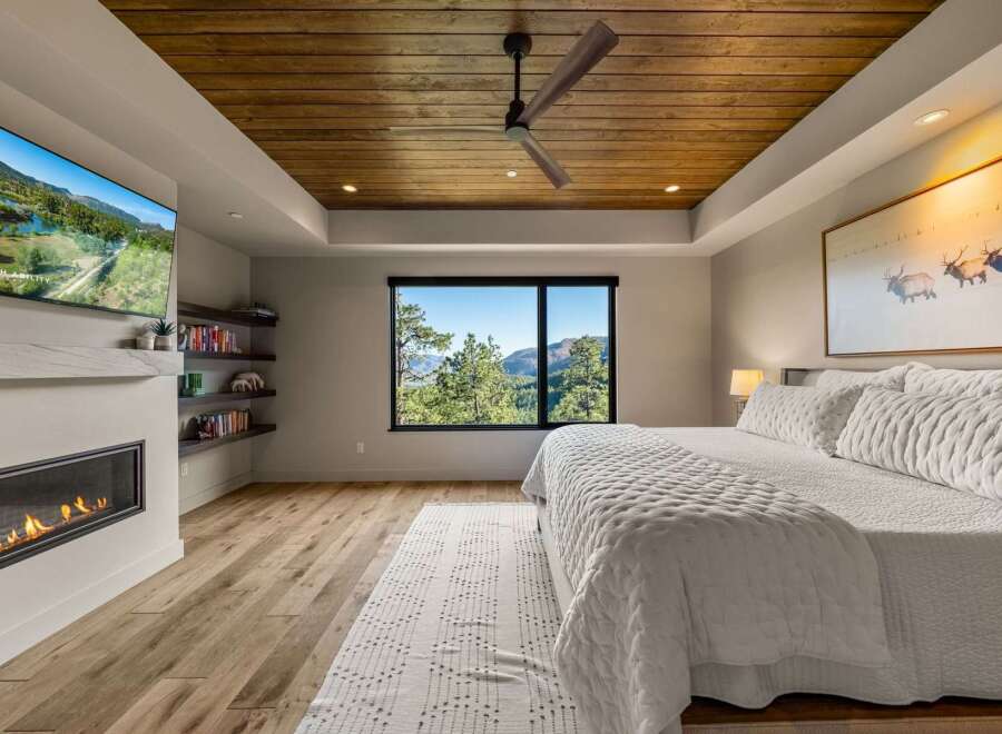 Experience luxury mountain living in this stunning bedroom featuring a modern gas fireplace and a wall-mounted television for ultimate relaxation.