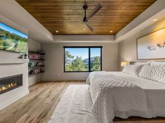 Experience luxury mountain living in this stunning bedroom featuring a modern gas fireplace and a wall-mounted television for ultimate relaxation.