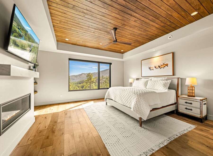 Experience luxury mountain living in this stunning bedroom, featuring a cozy fireplace and a large window with breathtaking views.